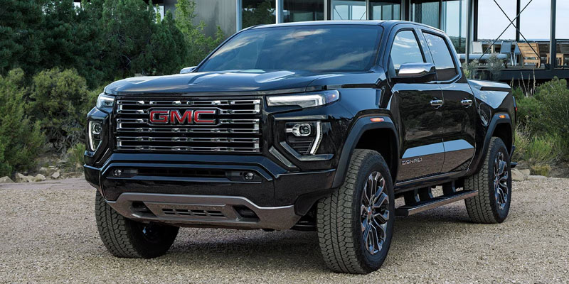 A black GMC Canyon Denali pickup truck, parked outdoors with a rugged, modern design.