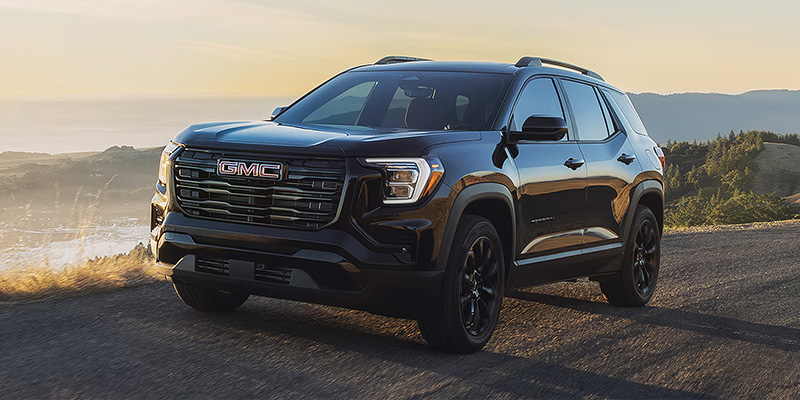 2026 GMC Terrain parked on a scenic road with hills in the background.