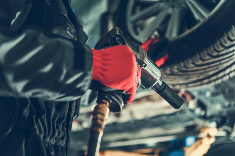 Mechanic servicing a vehicle’s tire and wheel with automotive tools.