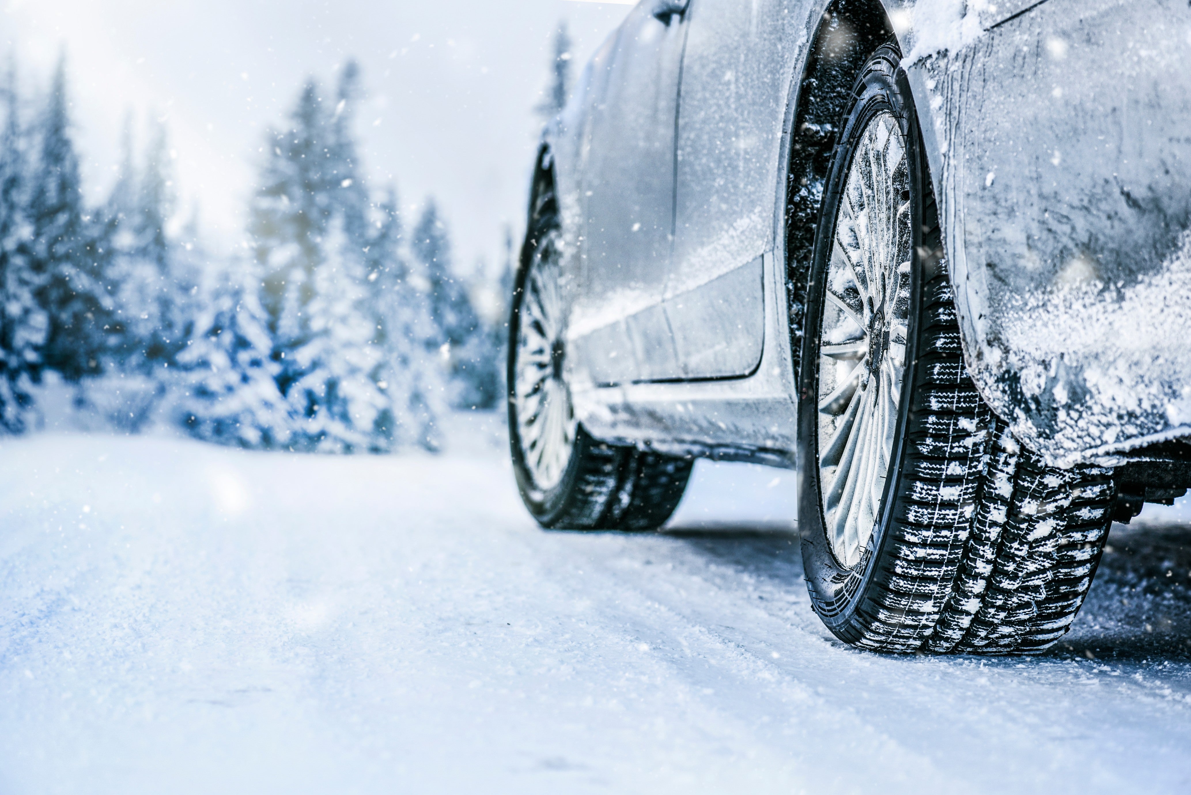 Close-up of car tires driving on a snow-covered road in winter.